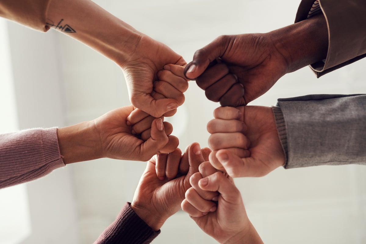 Diverse hands in a team huddle with fists together